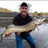 files/Angler_Holding_a_Muskie_Near_Shoreline.png